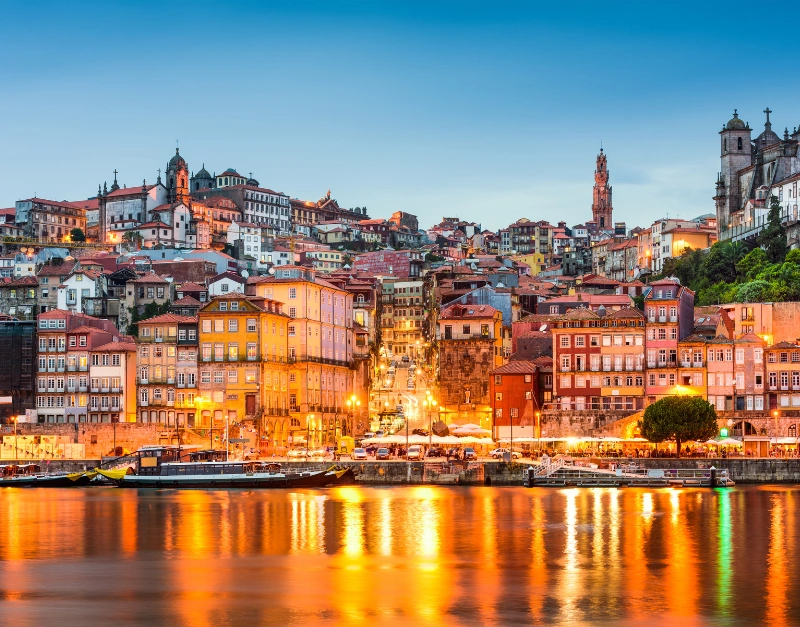 Porto cityscape along the Douro River at night with lights reflecting on the water